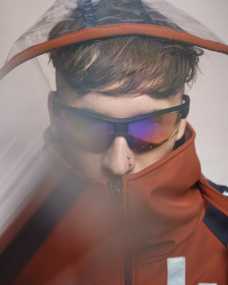 Gros plan capuche transparente et col, veste orange