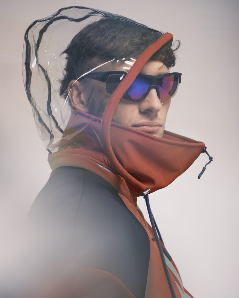 Détail capuche transparente amovible, veste orange et navy